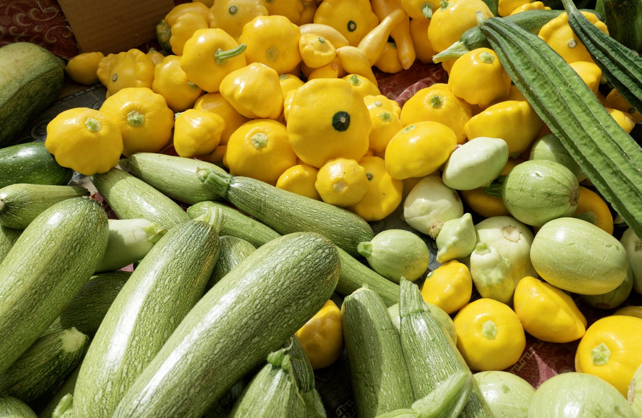 A colorful display of summer squash varieties at a farmers market stall
